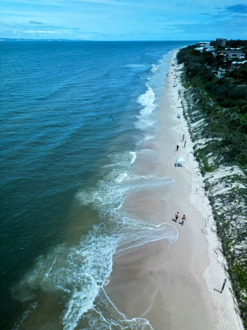 Free Discover the tranquil beauty of a sandy beach and the calm ocean from an aerial perspective. Stock Photo