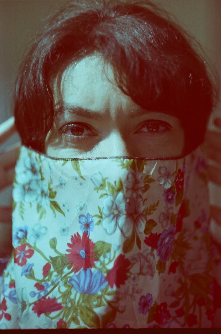 Film Photo Of A Woman Covering Her Face With A Fabric With A Floral Pattern 