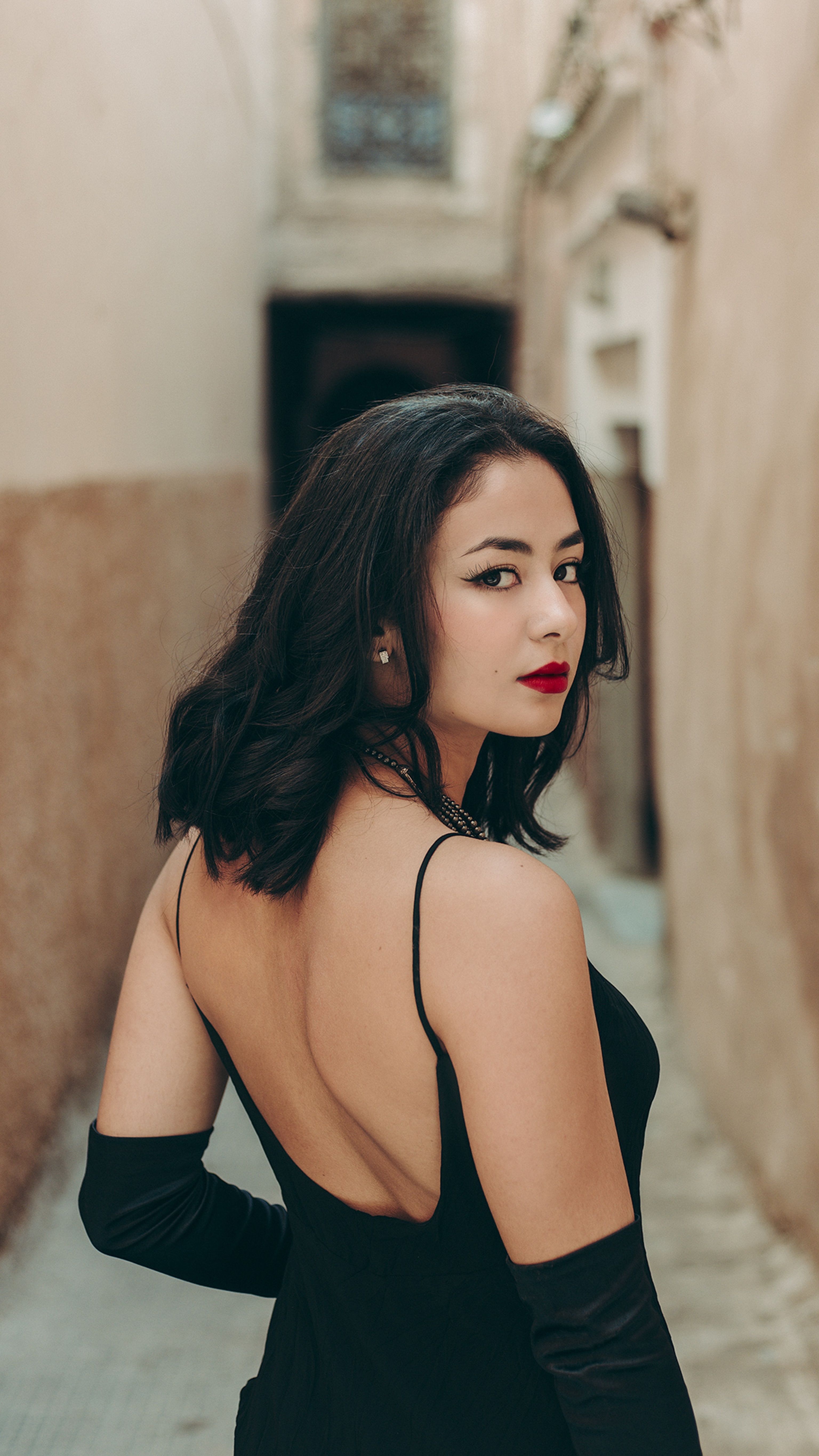 Free A woman in a black dress and gloves posing in an alley Stock Photo