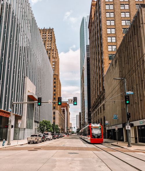 Free Vibrant cityscape of downtown Houston featuring a red tram, tall buildings, and an empty urban street. Stock Photo