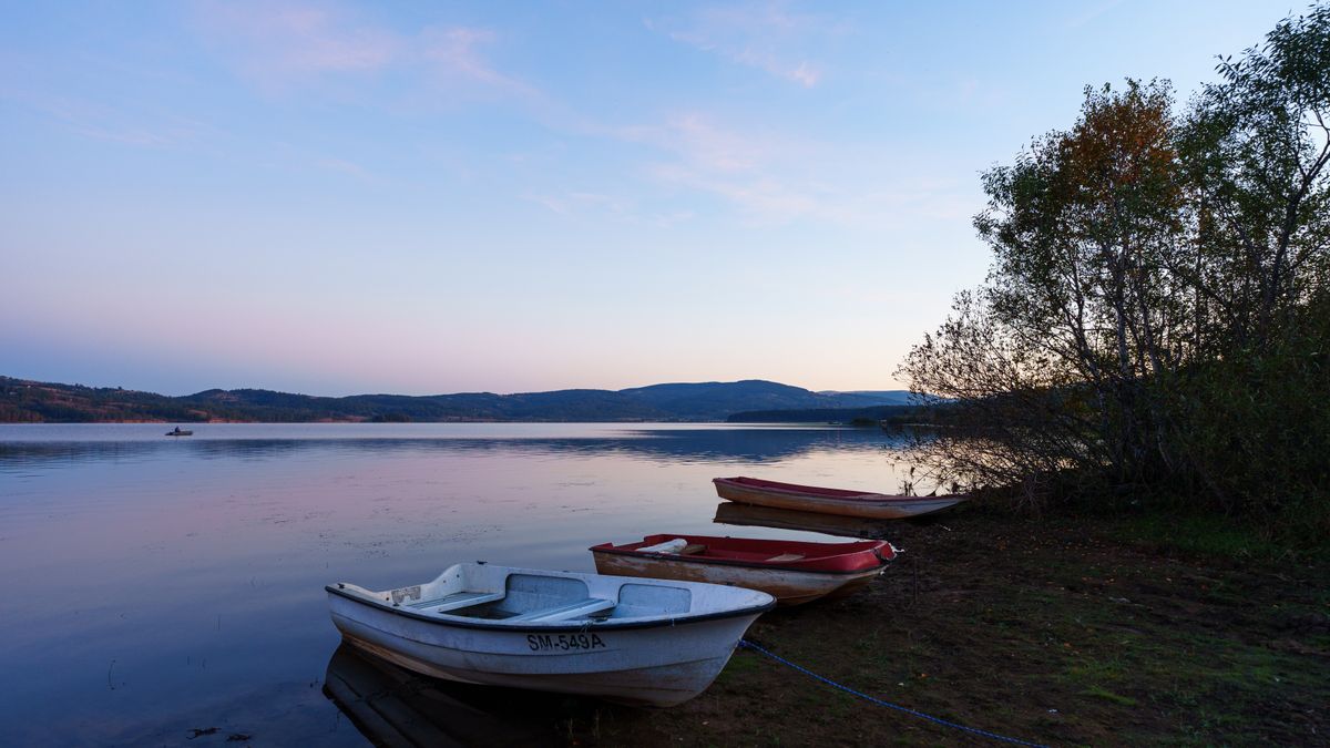 Tranquil scene of boats moored at Vlasina Lake in Serbia at dusk, surrounded by serene nature.