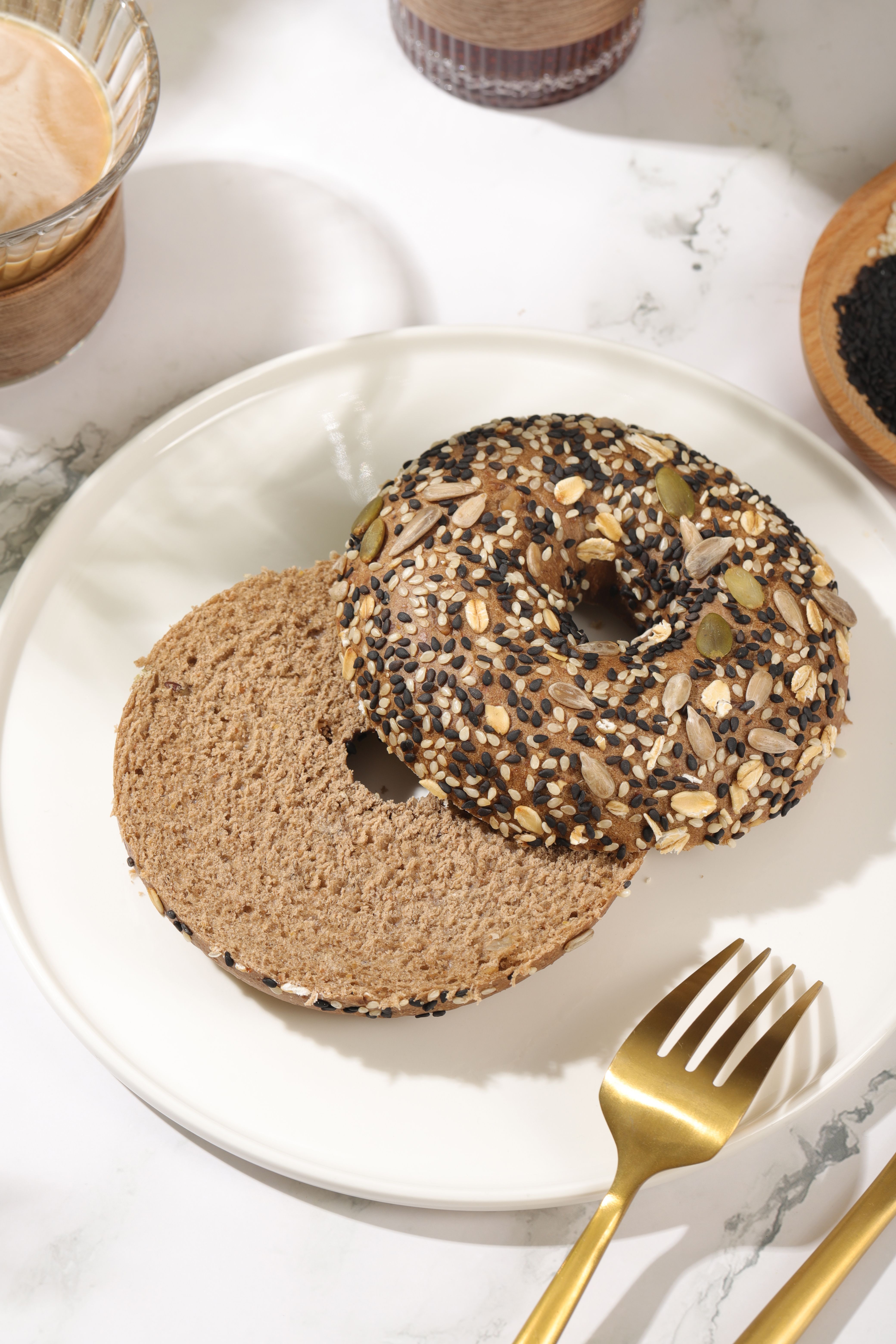 Six golden gluten-free bagels topped with everything seasoning and sesame seeds, cooling on a wire rack.