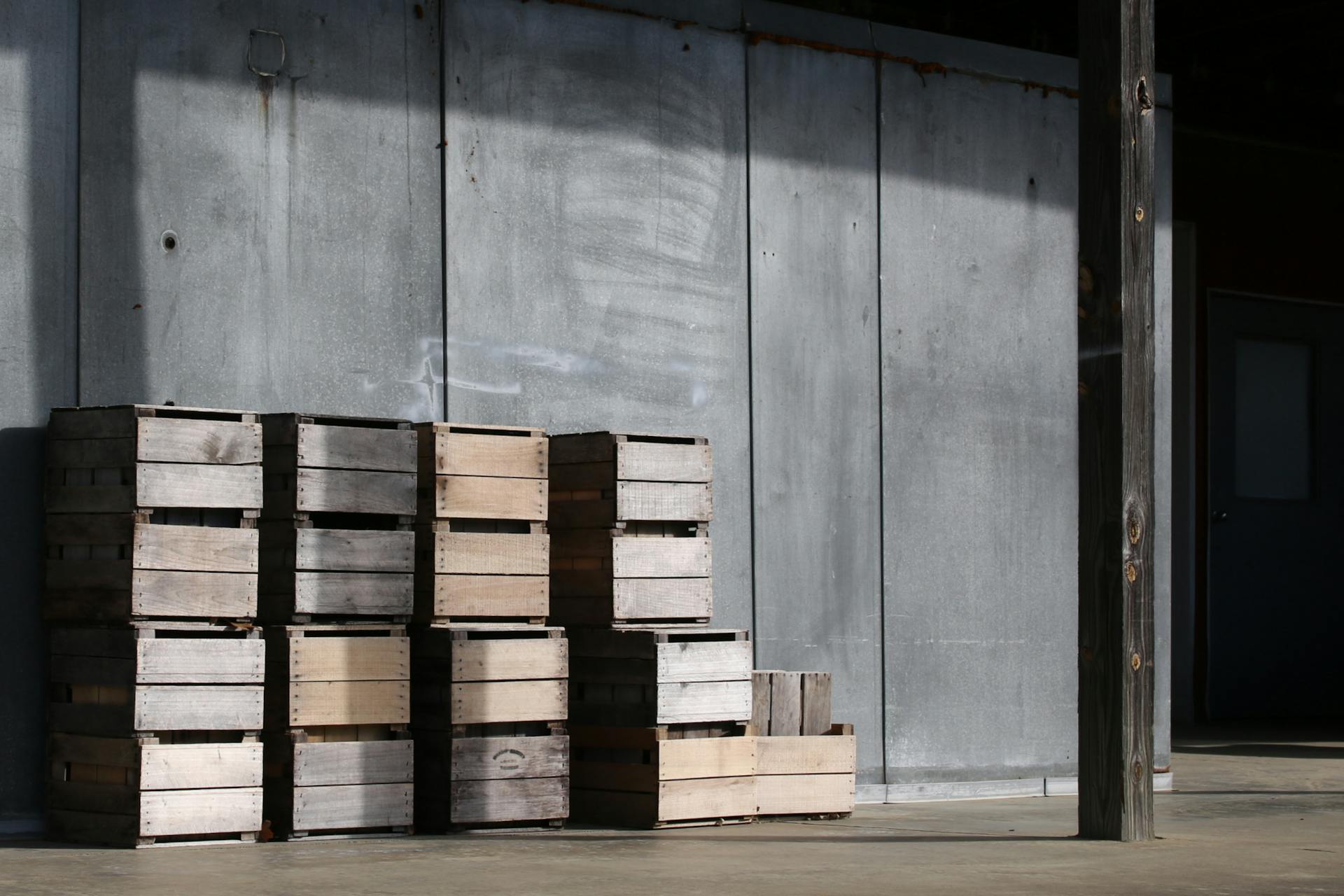 Wooden crates stacked against a metal wall in an industrial area, capturing rustic charm.
