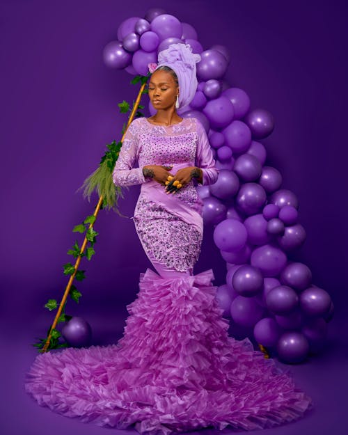 Model in Long Purple Dress Posing by Balloons in Studio