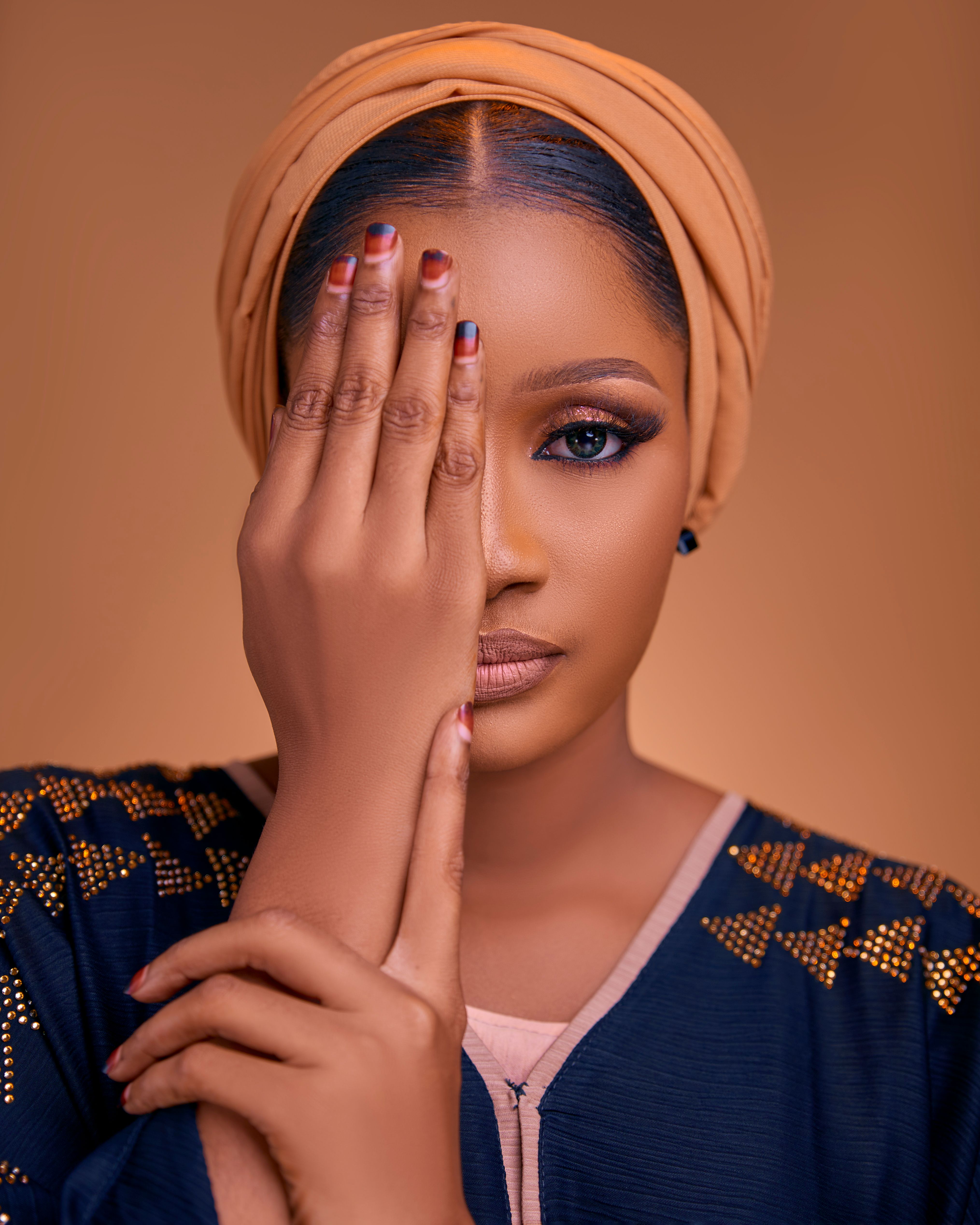 Close-up portrait of a woman with a headscarf covering one eye, showcasing style and elegance.