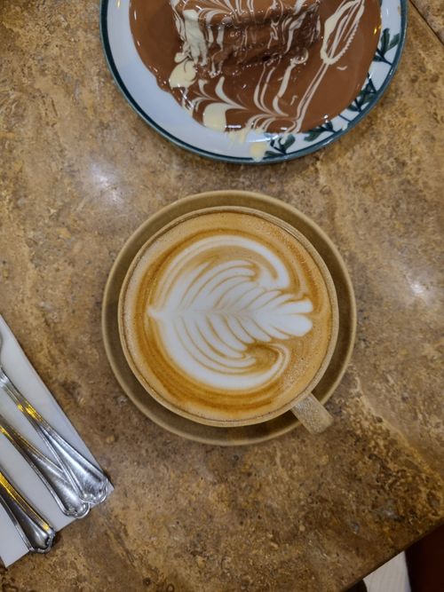 Free Top view of a cappuccino with latte art and dessert on a marble table. Perfect breakfast setting. Stock Photo
