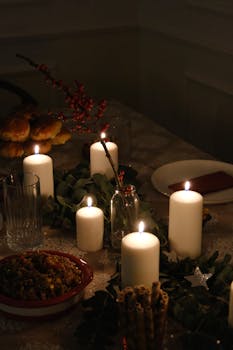 Elegant candlelit dinner table set with festive holiday decor, creating a warm ambiance.