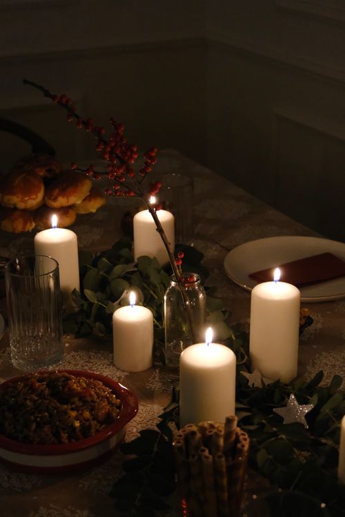 Free Elegant candlelit dinner table set with festive holiday decor, creating a warm ambiance. Stock Photo