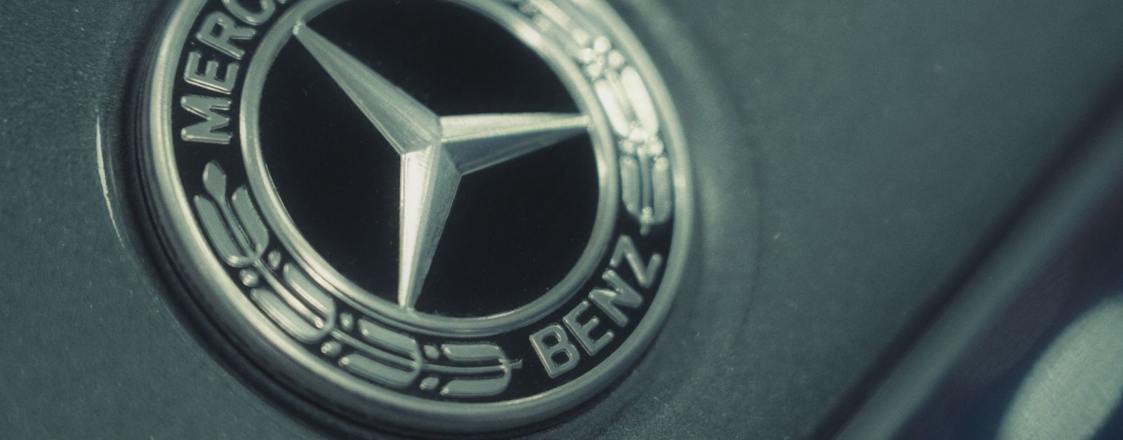 Detailed close-up of the Mercedes-Benz logo on a luxury car, emphasizing metallic finish.