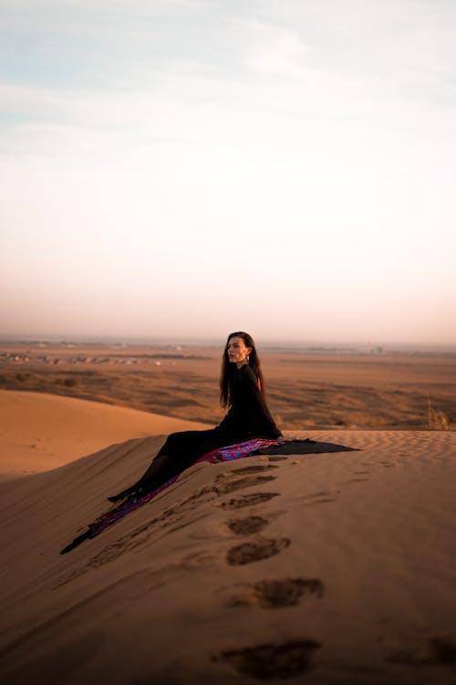 Woman Sitting on Dune on Desert