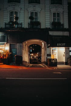 A dimly lit urban street at night featuring an arched passageway and classic architecture.