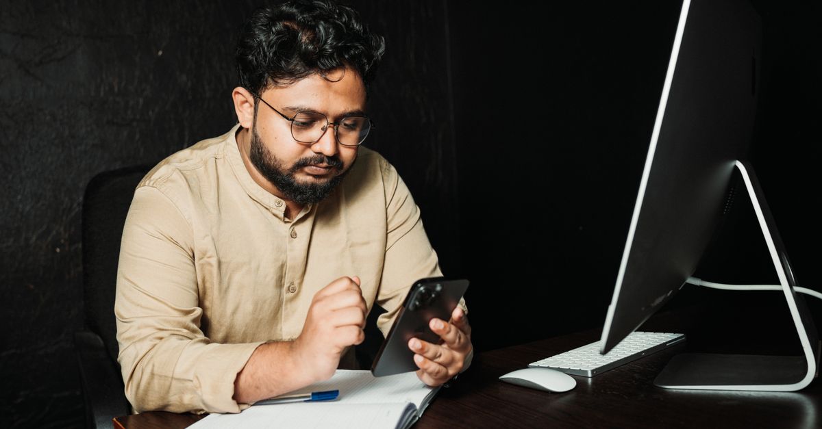 man reading document on smartphone at desk