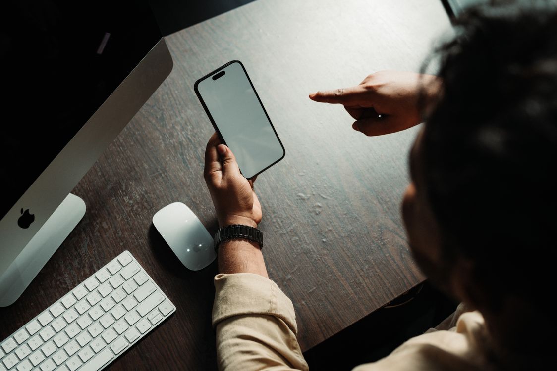 Person holding an iPhone at a desk, showing the phone's finish