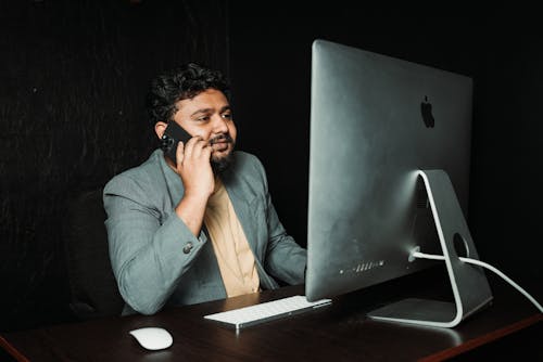 Free Man Working with Smartphone and Computer in Office Stock Photo