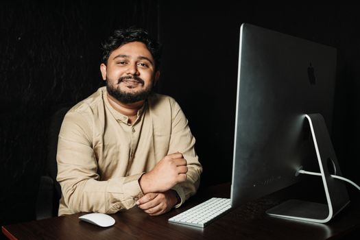 A confident man sitting at a desk with a computer, showcasing modern office technology.
