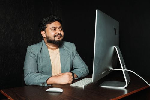 Free Confident man sitting at a desk with a computer in a modern office. Stock Photo