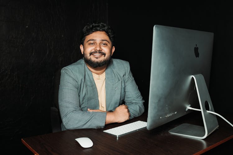 Smiling Businessman Sitting At Desk With Computer