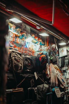 A vibrant market stall at night showcasing various backpacks with illuminated signs.