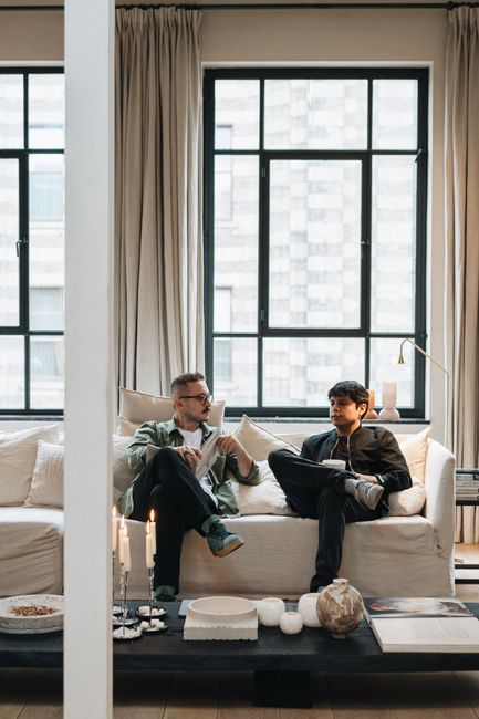 Two men sitting on a sofa having a relaxed conversation in an Amsterdam apartment.
