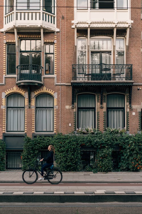 Cyclist Riding Along Brick Townhouse