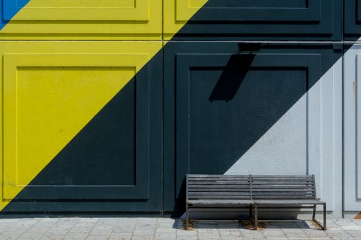 Modern urban scene with a colorful geometric wall and empty bench on a sunny day.
