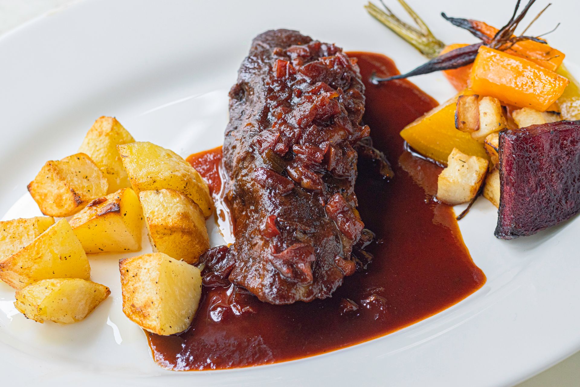 Roasted Beef with Fried Cubes of Potatoes on White Plate