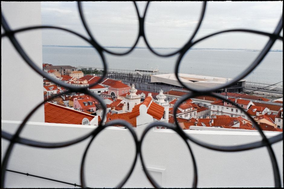 Captivating rooftop view in Lisbon with ocean backdrop and artistic metalwork foreground.
