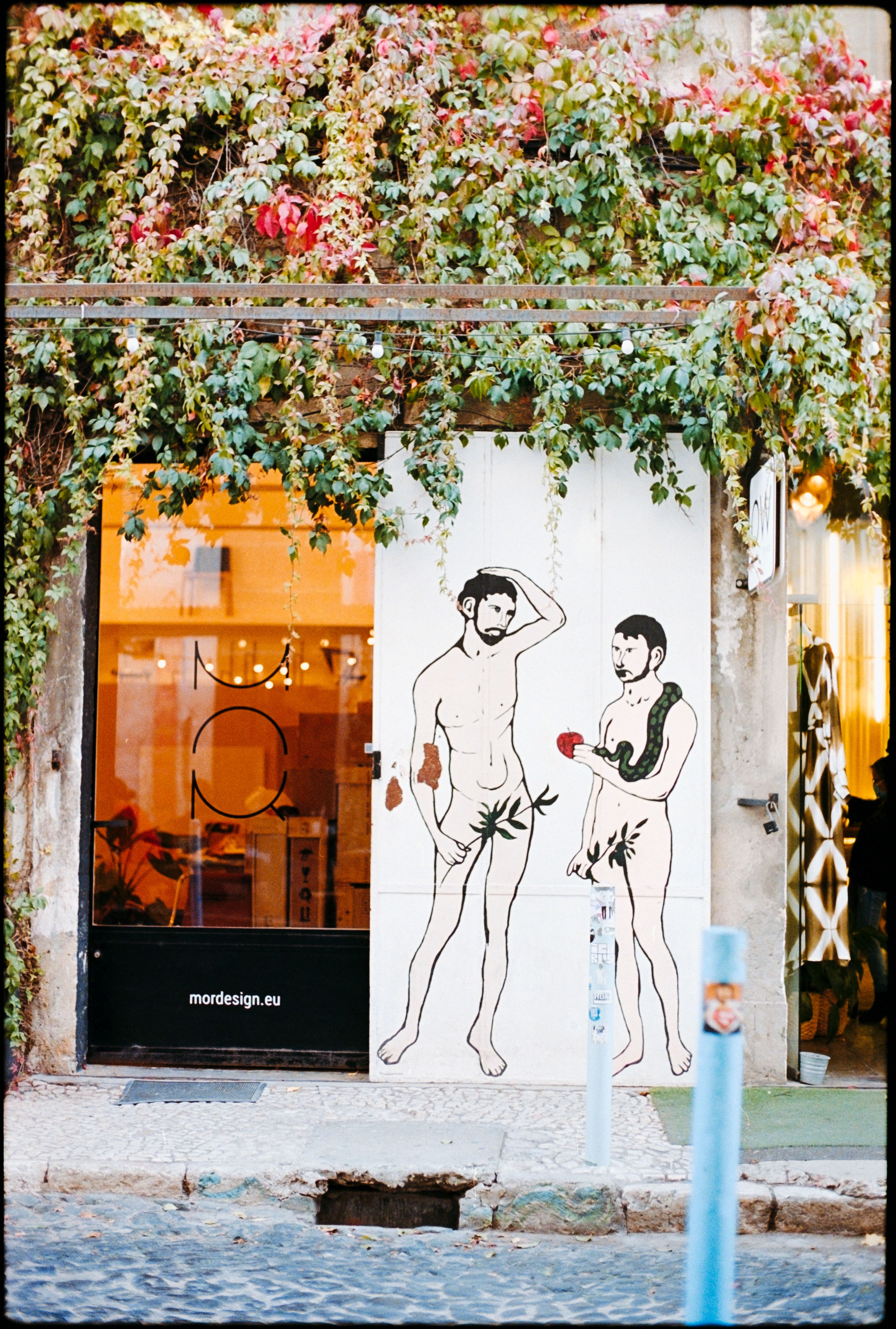 Colorful street art depicting Adam and Eve on a Lisbon building facade.