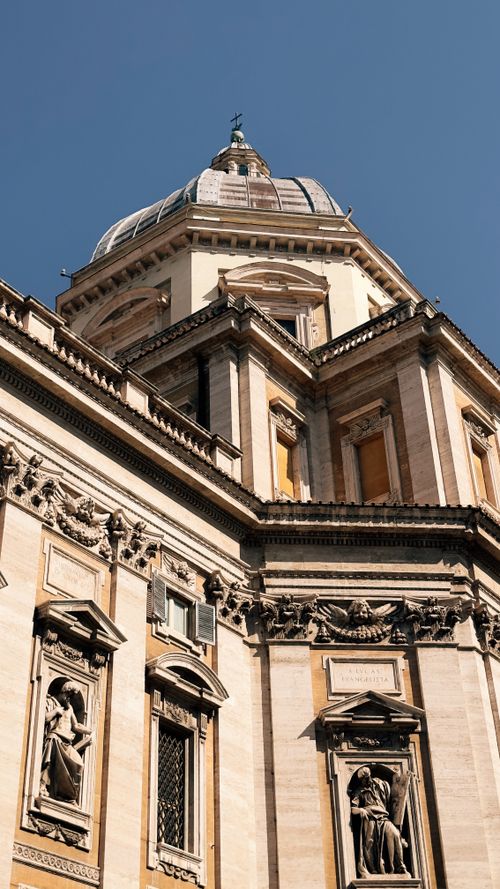 Free Low-angle view of the dome and ornate facade of a historic basilica in Rome, Italy. Stock Photo