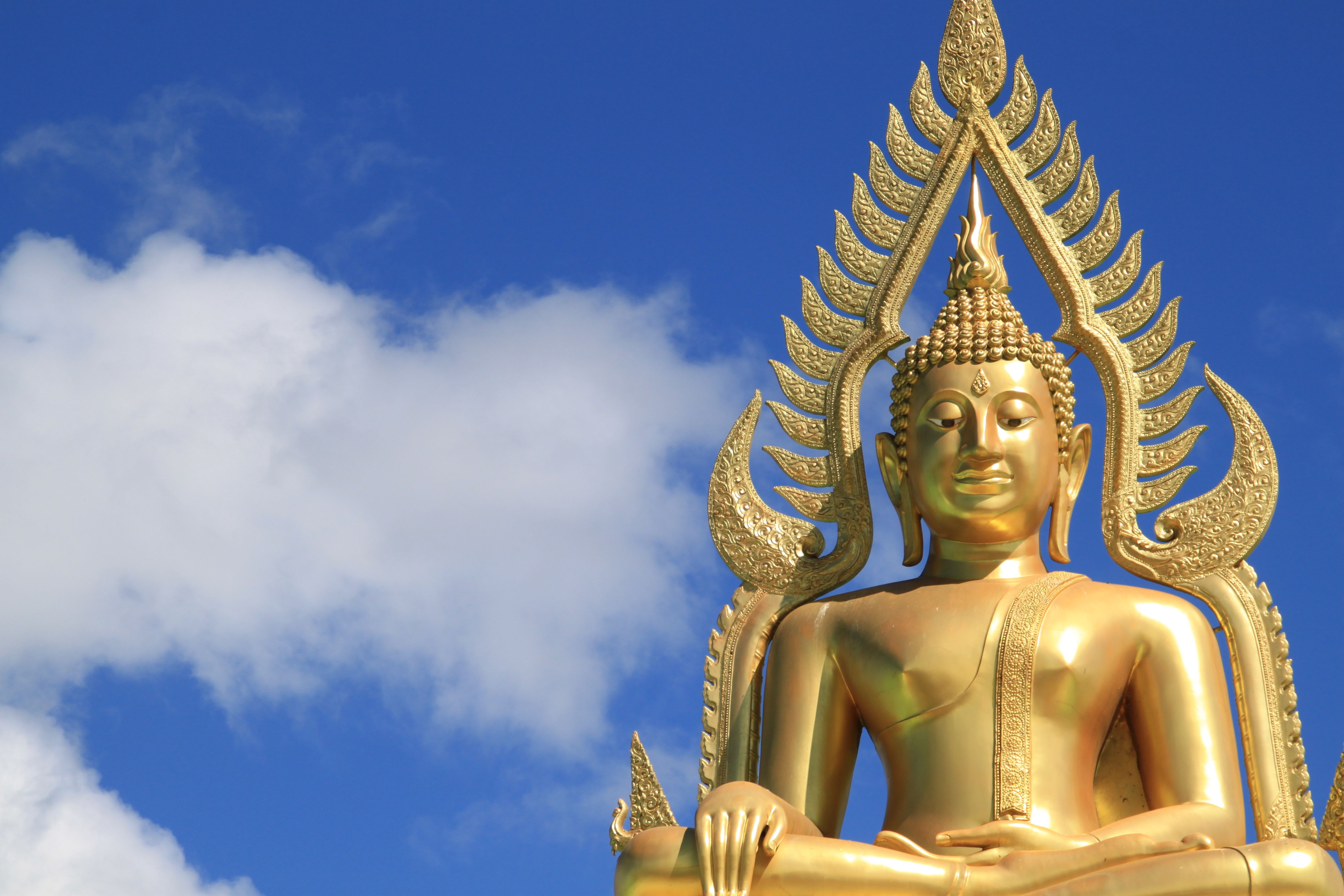 Majestic golden Buddha statue under a bright blue sky