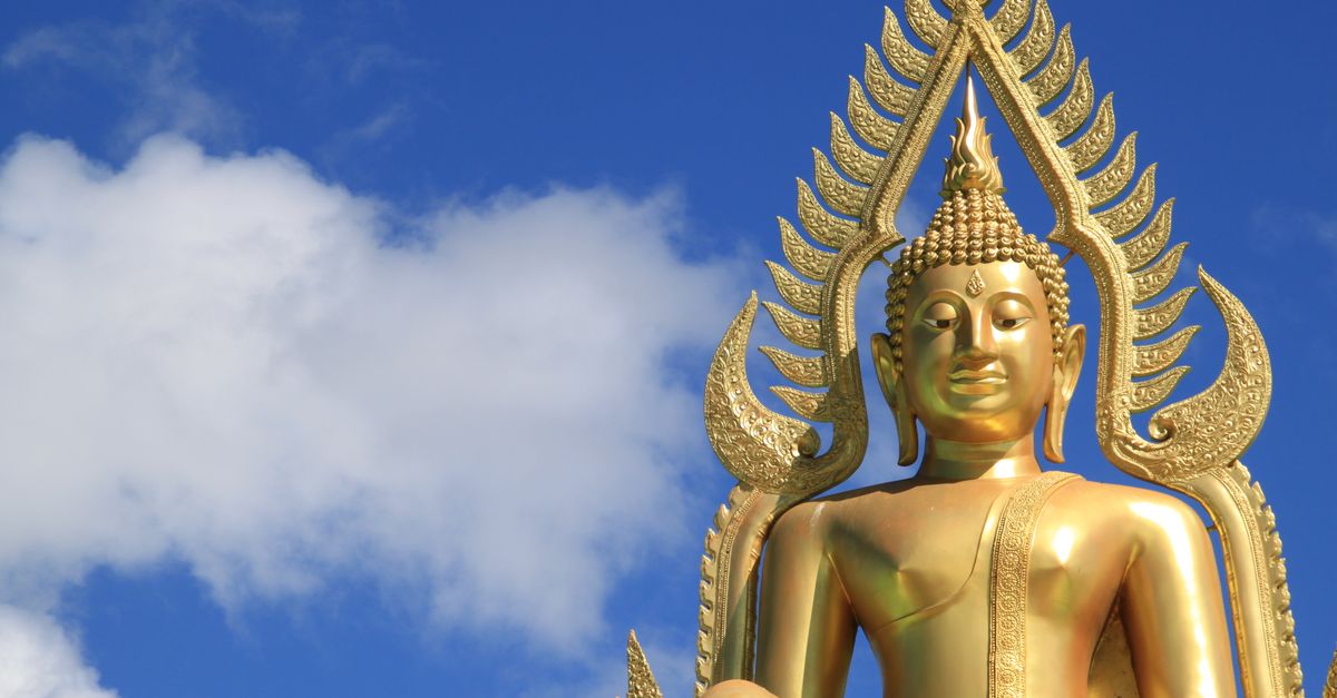 Majestic golden Buddha statue under a bright blue sky