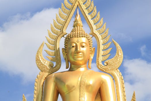 Majestic golden Buddha statue under a clear blue sky in Lampang, Thailand.
