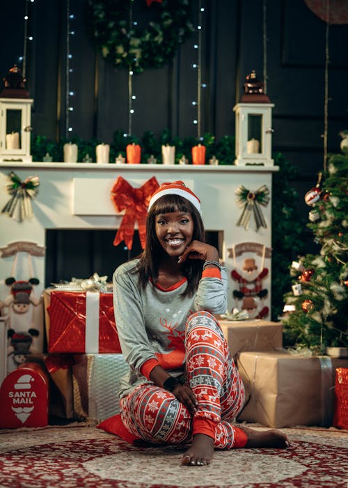 Smiling Woman in Christmas Pajamas and Santas Hat Among Gifts