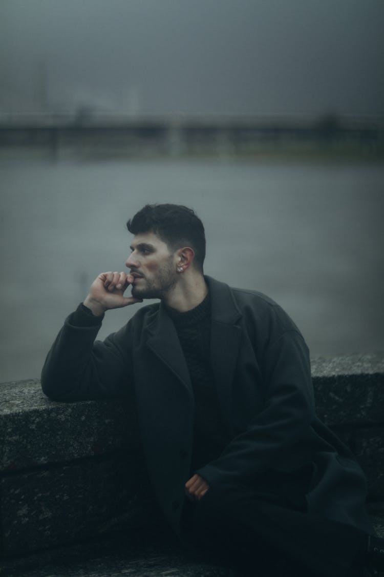 Man Wearing Black Coat In A Harbor 