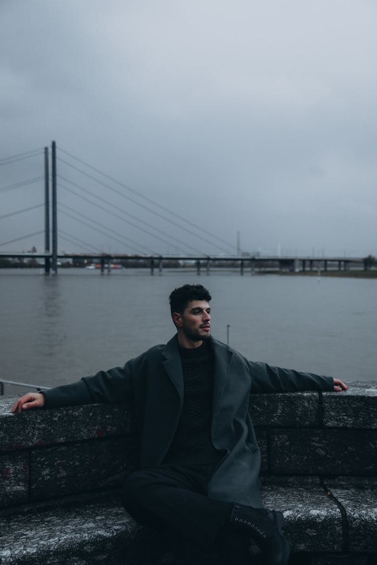 Man Wearing Black Coat In A Harbor 