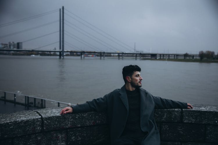 Man Wearing Black Coat In A Harbor 