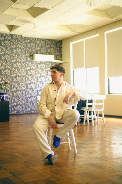 Model in a White Shirt with Black Buttons and Pants Sitting on a Chair