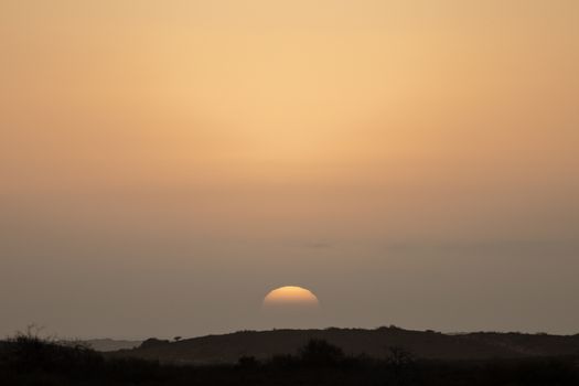 A tranquil sunset casting warm hues over an arid desert landscape.