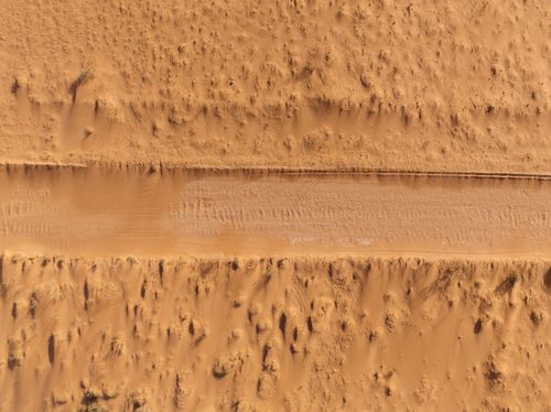 Free Drone shot capturing a sandy road cutting through the arid desert landscape near Exmouth Gulf, Australia. Stock Photo