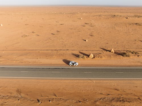 Car Parked on the Side of an Asphalt Road Through the Desert