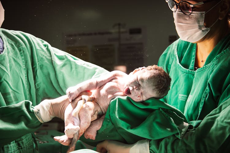 Doctors Holding A Newborn Baby During Labor