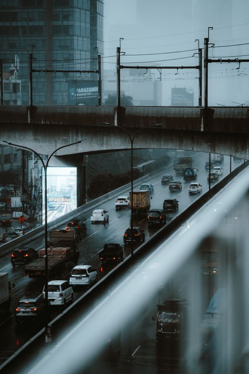 Free Heavy rain on a busy Jakarta highway with cars and urban structures in view. Stock Photo