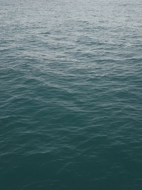 Free Close-up vertical shot of gentle ocean waves on a calm sea, showcasing a tranquil blue water surface. Stock Photo