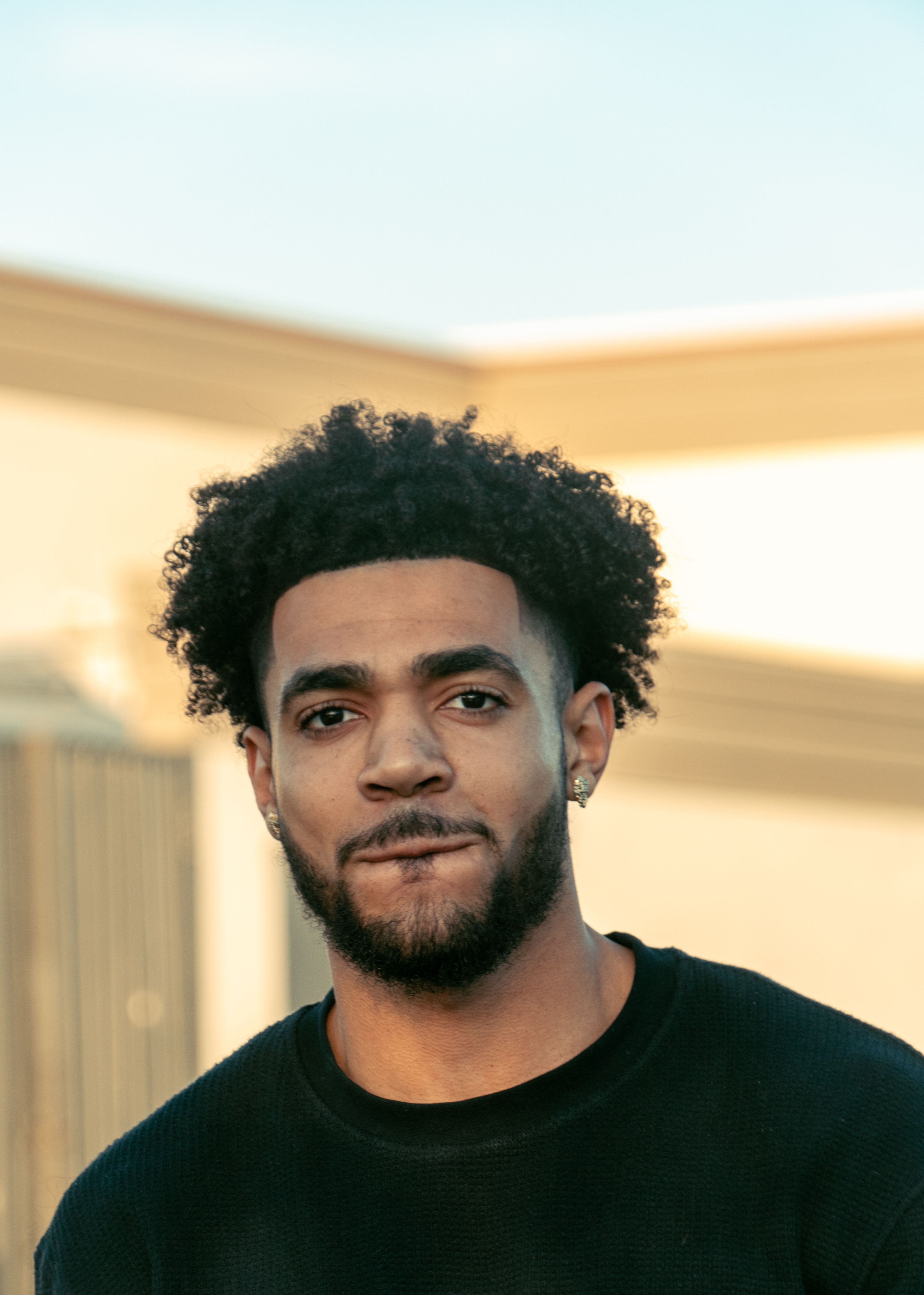 A young man in a casual black t-shirt poses outdoors. Ideal for lifestyle and fashion themes.