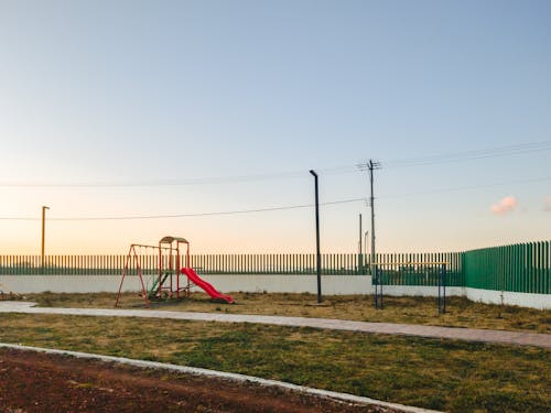 Бесплатное стоковое фото с зеленый забор, игровая площадка, красный слайд