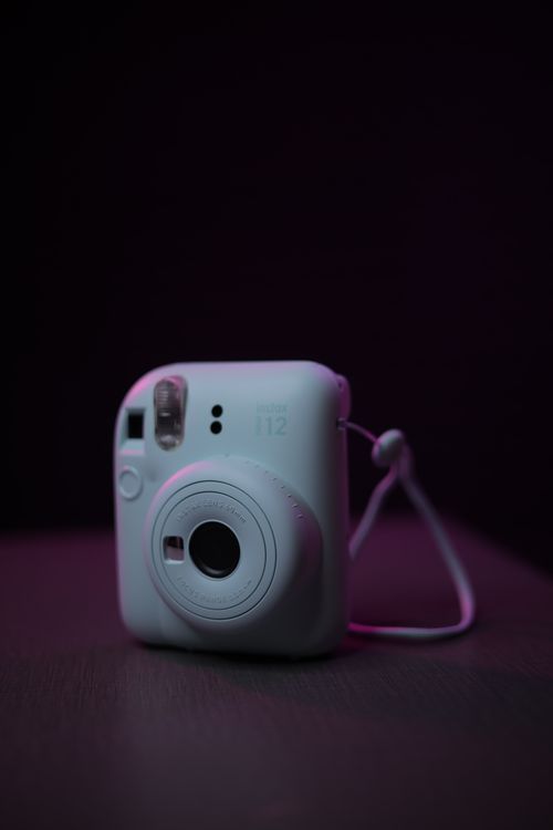 Free Close-up of a white instant camera with soft pink lighting, emphasizing its design and simplicity. Stock Photo