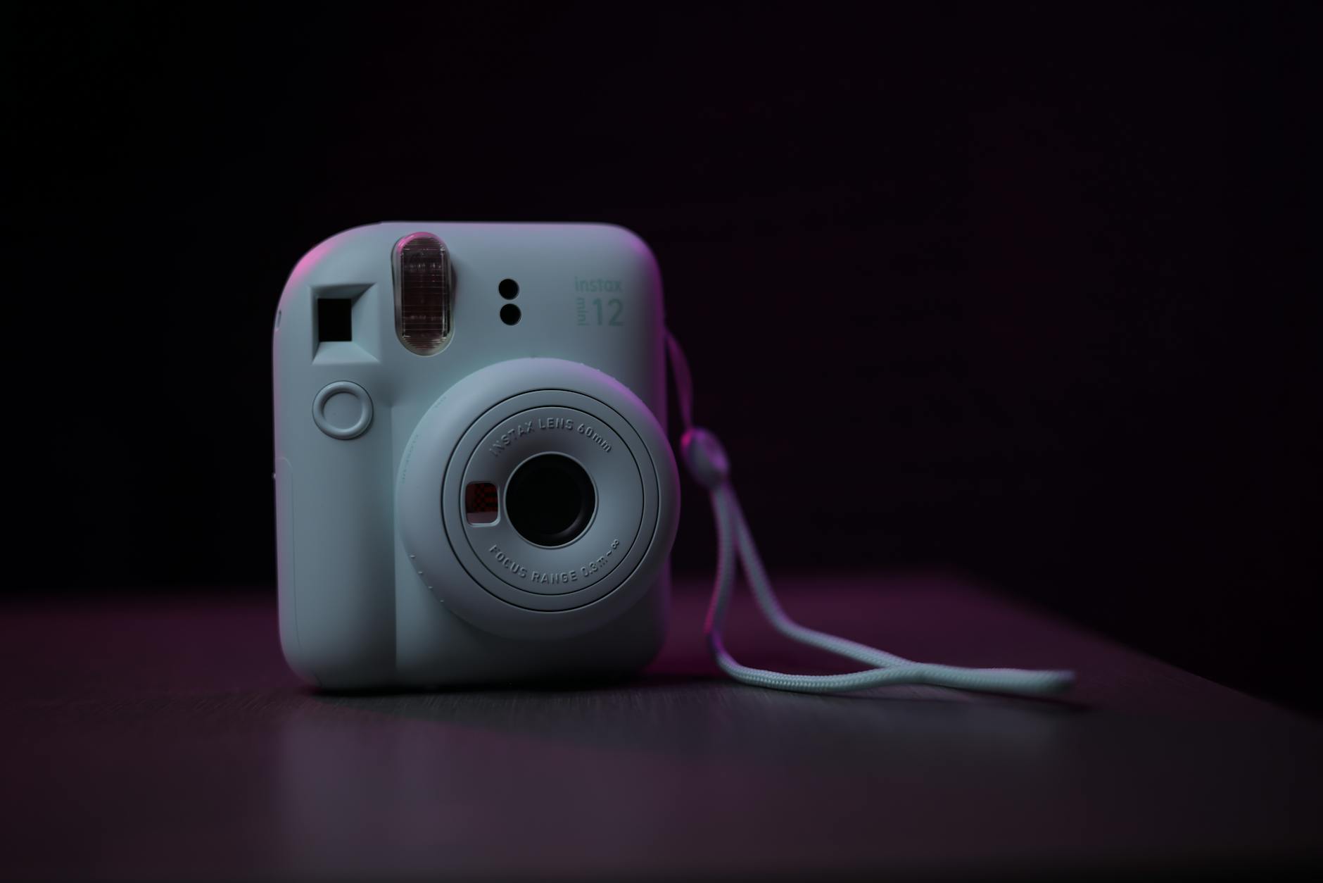 A white polaroid camera with a purple light