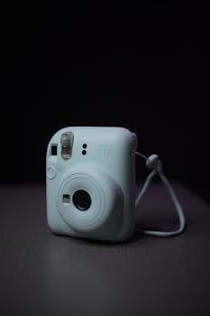 Close-up of a Fujifilm Instax Mini 12 camera against a dark background.