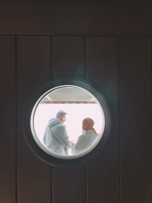 Man and Woman seen from behind a Circular Window in a Ferry 