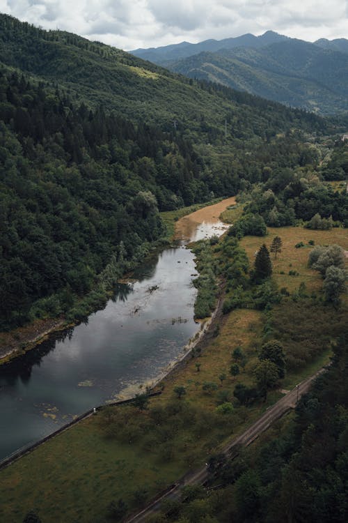 Aerial View of a River at the Foot of a Forested Mountain